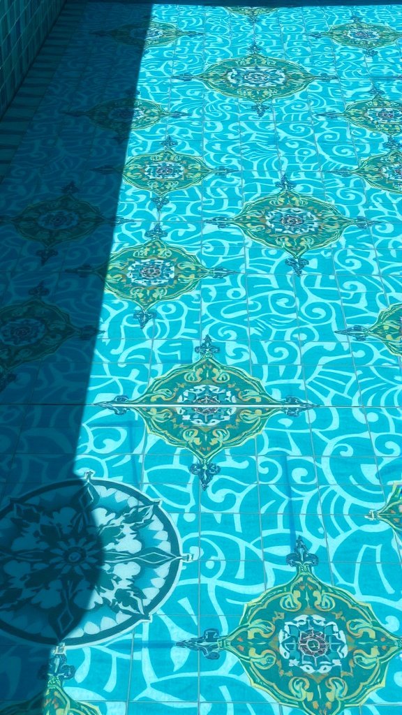 Artistic tile pattern on a pool floor featuring vibrant blue and decorative designs